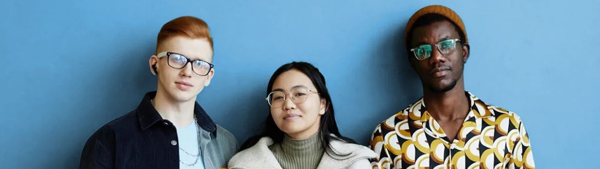 Three people in their 20s standing in front of a blue wall